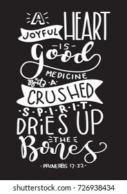 Hand Lettering A Joyful Heart Is A Good Medicine But A Crushed Spirit Dries Up The Bones on Black Background. BIble Lettering. Hand Lettered Quote. Modern Calligraphy. Inspirational Motivational Quote