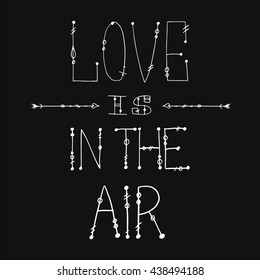 hand lettering - love is on the air - on the dark grey background with hand drawing arrows