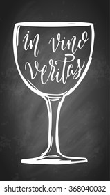 Hand lettering in vino veritas in wine glass sketch frame. On black chalkboard background. Vector illustration.