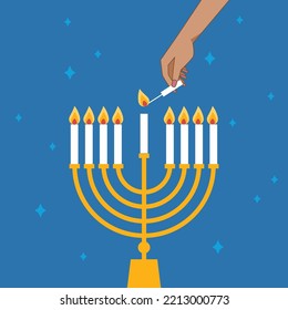 Hand Lighting Candle On Metal Hanukkah Menorah On Surface Against Blue Background. Man lighting up candles in menorah. Jewish Woman Celebrating Holidays Hanukkah