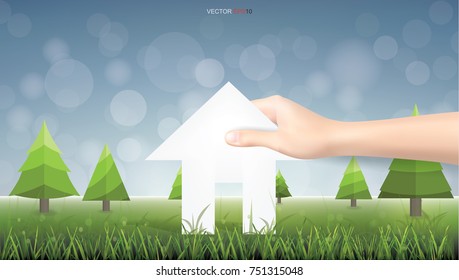 Hand pick a paper house on green yard area. Conceptual image of real estate idea. Vector illustration.