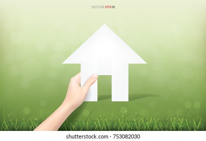 Hand pick a paper house on green yard area. Conceptual image of real estate idea. Vector illustration.