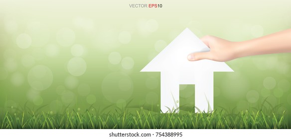Hand pick a paper house on green yard area. Conceptual image of real estate idea. Vector illustration.