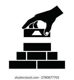 A hand placing a brick on top of a stack of bricks, symbolizing construction and building