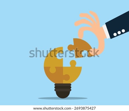 hand placing the final puzzle piece into a light bulb. Businessman with puzzles bulb idea