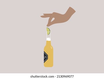 Hand putting a slice of lime into a beer bottle neck, fresh alcoholic drink