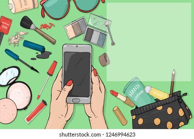 Hand with a smartphone and colourful items of women's cosmetics on a green background. Decorative cosmetics for face and nails. For beauty, fashion magazine, mobile apps. Mock up. Template.