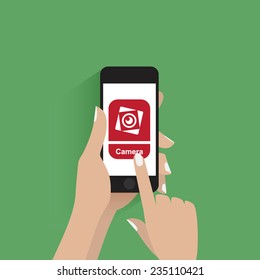 Hand touching smartphone with camera icon on the screen.