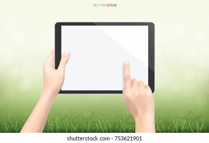 Hand touchscreen tablet computer in green grass field area with light blurred bokeh background. Vector illustration.
