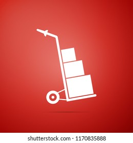 Hand truck and boxes icon isolated on red background. Dolly symbol. Flat design. Vector Illustration