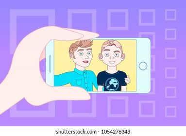 Hand mit Smartphone für Selbstfoto von zwei jungen Leuten