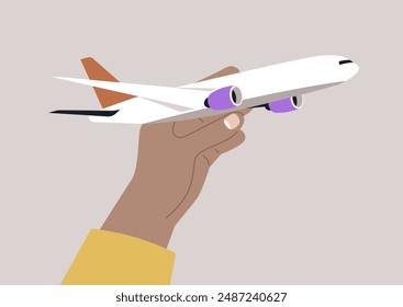 A hand, wearing a yellow sleeve, holds a white toy airplane with purple engines, prepared to launch it into the air