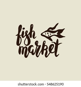 Hand written with brush pen and inc inscription fish market, lettering, calligraphy with fish silhouette. Vector. Could be used for fish restaurant, market.