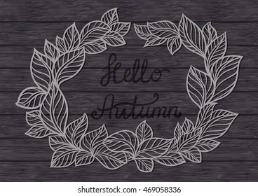 Hand written sign Hello Autumn on wood texture. Lettering  text with frame of leaves.