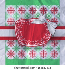Hand-drawn label and paper bow on patterned background with red and green snowflakes  and old crumpled paper texture, Christmas background