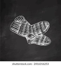 Hand-drawn sketch of knitted socks on chalkboard background. Knitwear, handmade concept in vintage doodle style. Engraving style.	