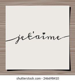 Hand-drawn typographic design template for Valentine's Day. Paper note on wood background mock-up. Je t'aime - I Love You in French.
