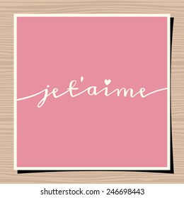 Hand-drawn typographic design template for Valentine's Day. Paper note on wood background mock-up. Je t'aime - I love you in French.