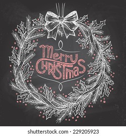 Hand-lettering Merry Christmas with Christmas wreath on blackboard with chalk