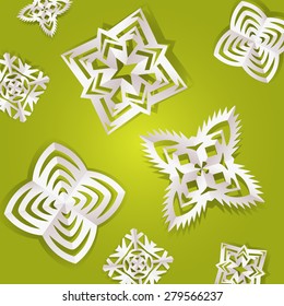Handmade paper snowflakes on green background.