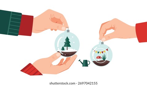 Hands crafting and displaying two unique glass terrarium ornaments, featuring a snowy forest with pine trees and a colorful miniature garden scene.