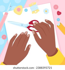 Hands of a dark-skinned woman with scissors and sewing tools