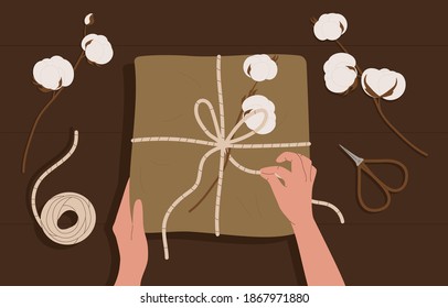 Hände und Geschenkbox auf dem Tisch. Papierkarton aus Kunsthandwerk mit dekorierten Baumwollköpfen. Draufsicht mit Elementen: Geschenkbox, Schere und Baumwollköpfe. Flaches Cartoon, Vektorgrafik






