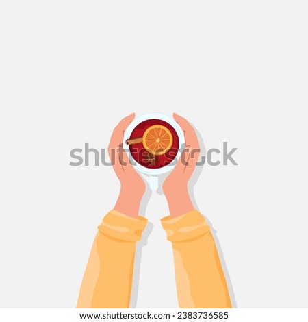 Hands hold a cup of fragrant hot mulled wine with various spices. Top view.