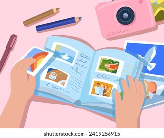 Hands hold a photo album and put photographs into it. There is an album, a camera, pencils and photographs on the table. Album of happy memories, immortalizing moments of vacation and vacation photos,