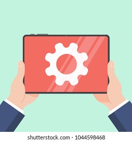 Hands holding black tablet device isolated on light blue background. Pad tablet in human's hands with gears on screen flat design vector illustration.  Technology concept of maintenance cog symbol.