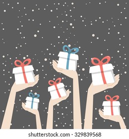 Hands are holding christmas presents with red and blue ribbons on the snowing background.