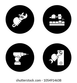 Hands holding construction tools glyph icons set. Lump hammer, plumbing wrench, spanner, cordless drill. Vector white silhouettes illustrations in black circles
