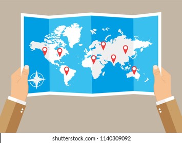 Hands holding folded paper map of world with color point markers. World map countries. vector illustration in flat design on brown background