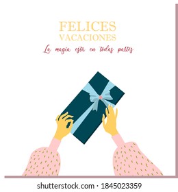Hands are holding the gift. Unfolding the gift. Festive surprise box. Christmas minimalistic postcard. Inscription in Spanish: Happy Holidays.
