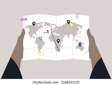 Hands holding a global map with folding lines and geo pins, travel concept