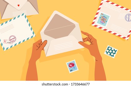 Hands holding an opened envelope. Envelopes, post stamps and post cards on the table. Top-down view.  Modern vector illustrated banner, card design. Correspondence and postal delivery concept.