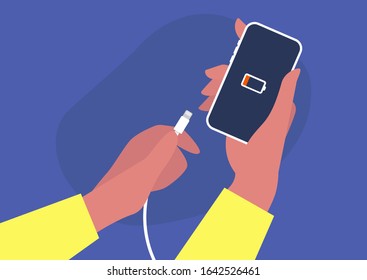 Hands holding a phone and a charger, low battery, white cable, new technologies