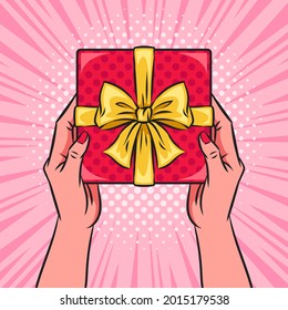 Hands holding red gift box or present with a bow and ribbons. Pop art vector comic illustration. Top view.
