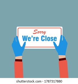 Hands holding "Sorry We're Close" ,sign label on the door store is closing earlier for social distancing in covid-19 