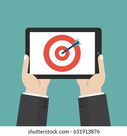 Hands holding tablet with target icon in a flat design