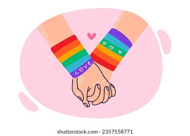 Hands of LGBT lovers in rainbow bracelets, for concept problems of tolerance towards gays and lesbians. LGBT or LGBTq couple holding hands to show unity and harmony in relationship