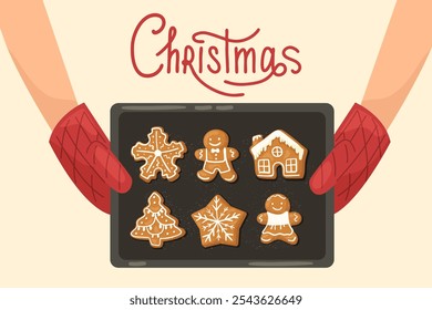 Hands in oven mitts holding a baking tray with hot gingerbread Christmas cookies. Christmas text