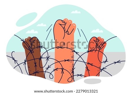 Hands of protesters are clenched into fist near barbed wire at border intended to restrict movement of illegal migrants. Fist is symbol of protest action of prisoners against deprivation of liberty 