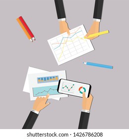 Hands of two persons holding graphics on paper and on mobile phone