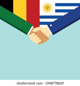 El apretón de manos y dos banderas Bélgica y Uruguay. Ilustración vectorial de estilo plano.

