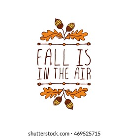 Hand-sketched typographic element with acorns and text on white background. Fall is in the air