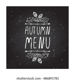 Hand-sketched typographic element with acorns and text on blackboard background. Autumn menu