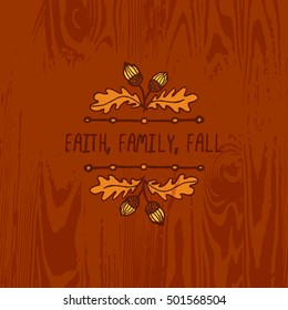 Hand-sketched typographic element with acorns and text on wooden background. Faith family fall