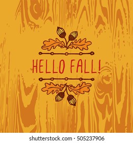 Hand-sketched typographic element with acorns and text on wooden background. Hello fall