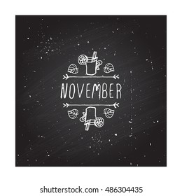 Hand-sketched typographic element with mulled wine, leaves and text on blackboard background. November